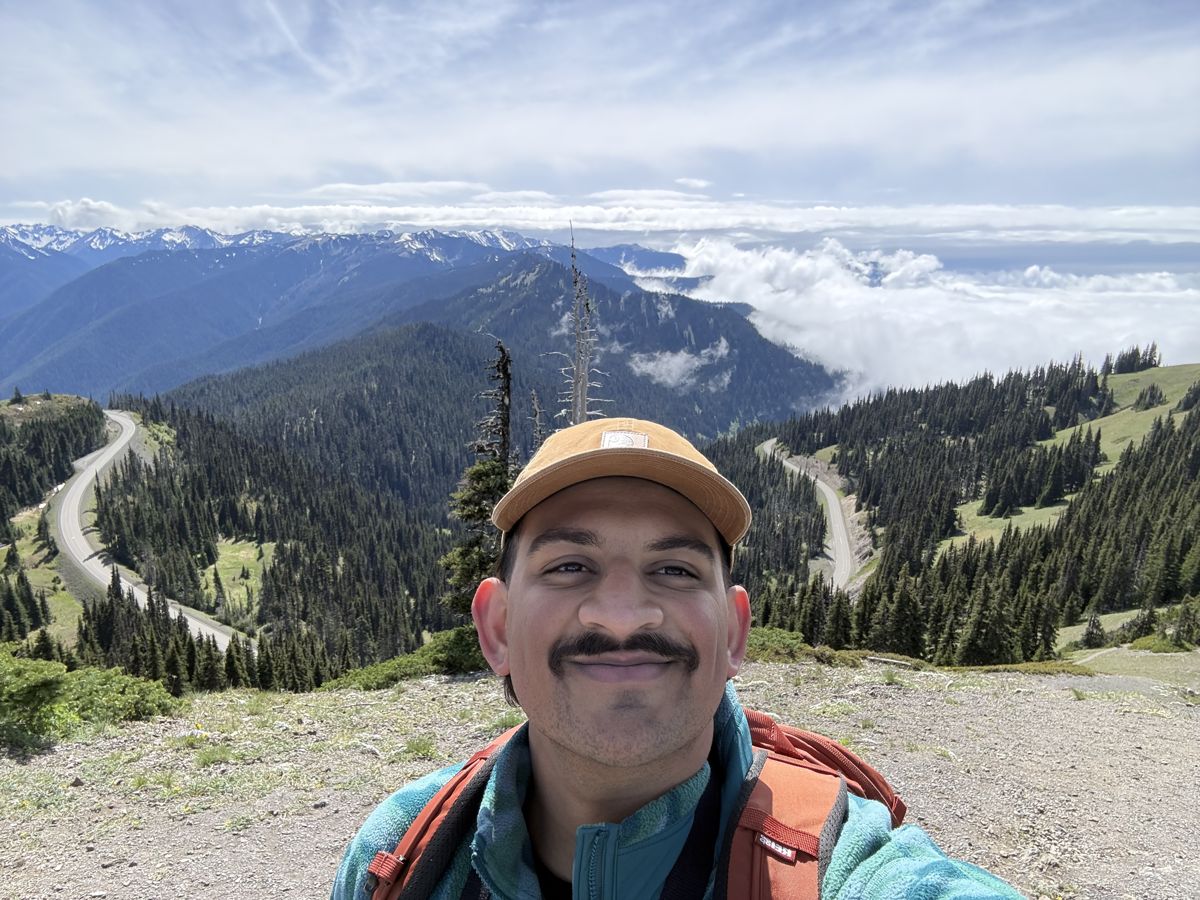 Selfie overlooking forested valleys and snowy peaks in the alpine region of Olympic National Park